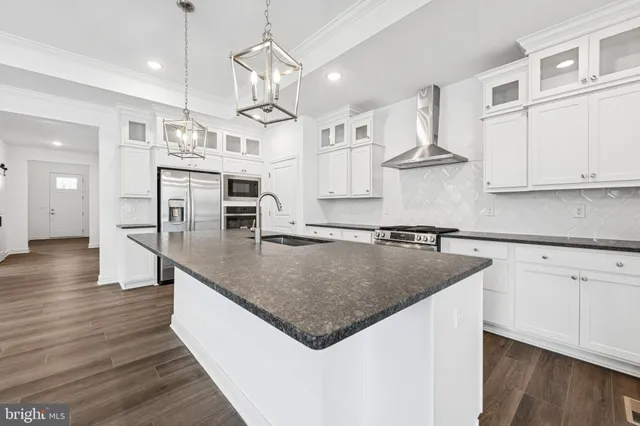 a kitchen with stainless steel appliances granite countertop a sink a stove and a wooden floors
