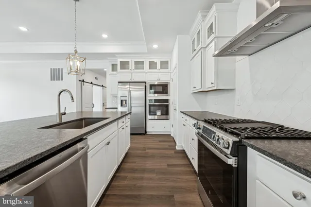 a kitchen with stainless steel appliances granite countertop a sink stove and cabinets