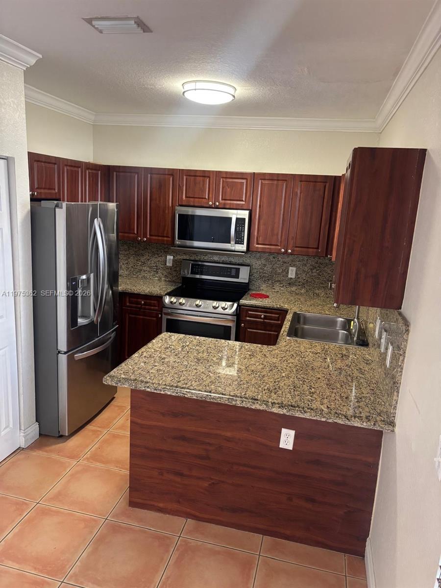 371 Northeast 26th Terrace, Unit 101 Homestead, FL 33033 - Photo 2 of 10 a kitchen with kitchen island granite countertop a sink a stove and a refrigerator