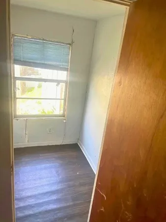 a view of an empty room with wooden floor and a window