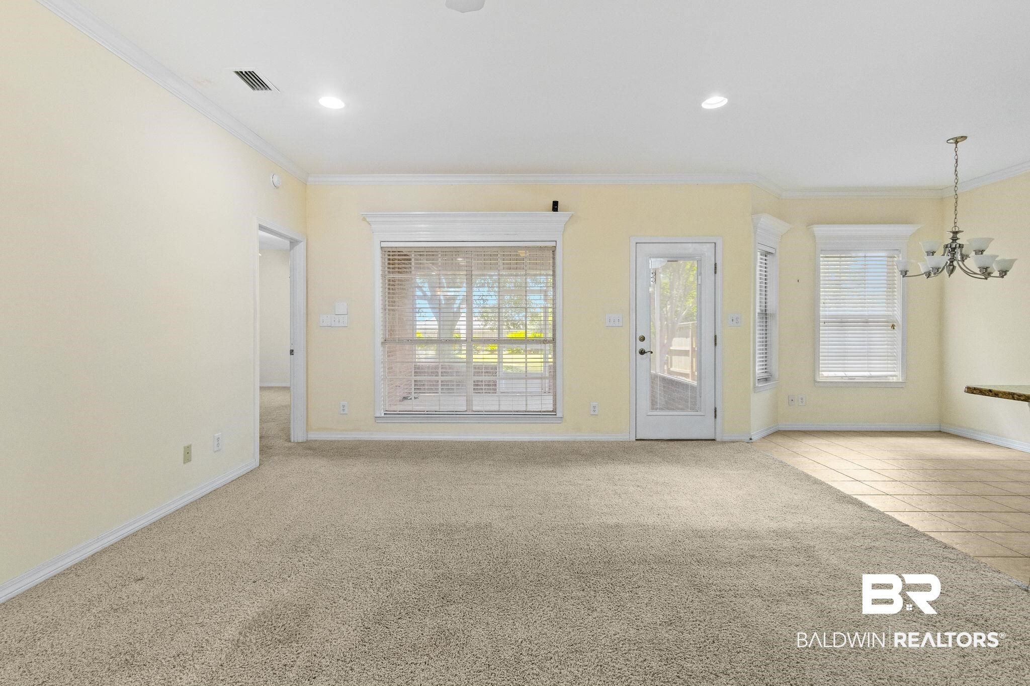 166 Club Drive Fairhope, AL 36532 - Photo 9 of 41 Unfurnished living room featuring ornamental molding, a notable chandelier, and light carpet