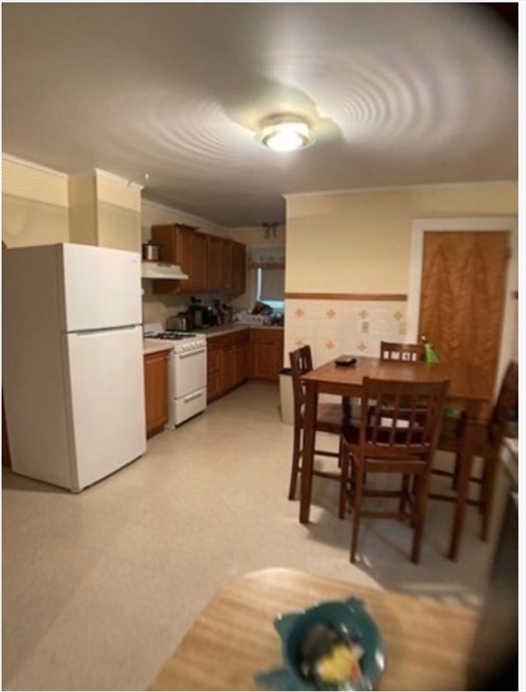 90 Massasoit Street, Unit 90 Waltham, MA 02453 - Photo 3 of 15 a kitchen with a table chairs and a refrigerator