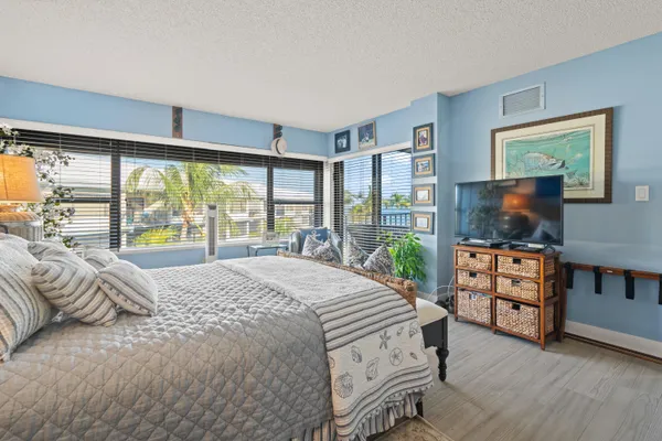 a bedroom with a bed and large windows