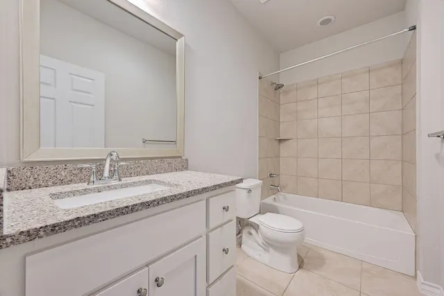 a bathroom with a granite countertop sink a toilet and bathtub
