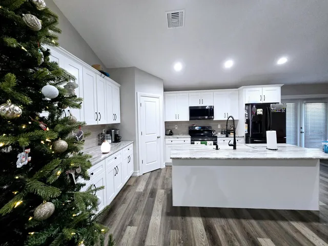a large white kitchen with wooden floor