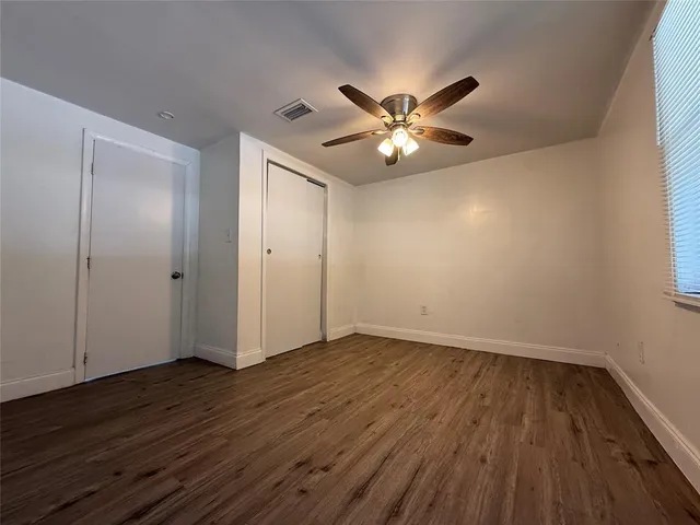 an empty room with wooden floor chandelier fan and closet area