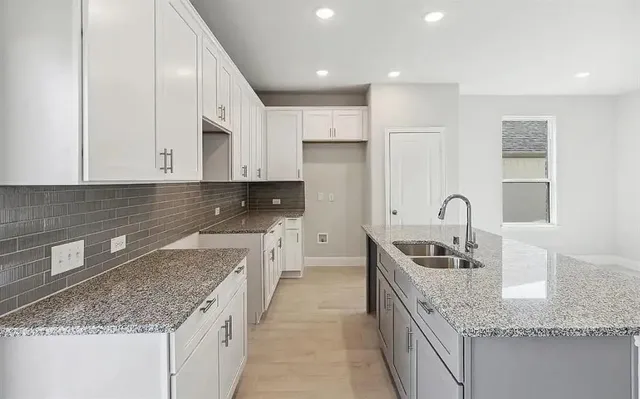 a kitchen with granite countertop a sink a stove and cabinets