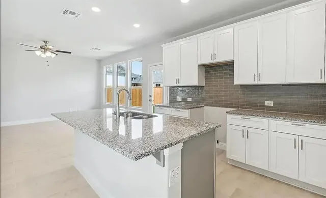 a kitchen with kitchen island granite countertop a sink a center island and cabinets