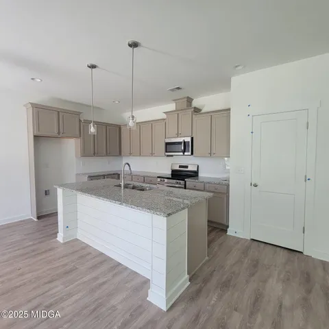 a kitchen with stainless steel appliances granite countertop a sink a stove a refrigerator and white cabinets
