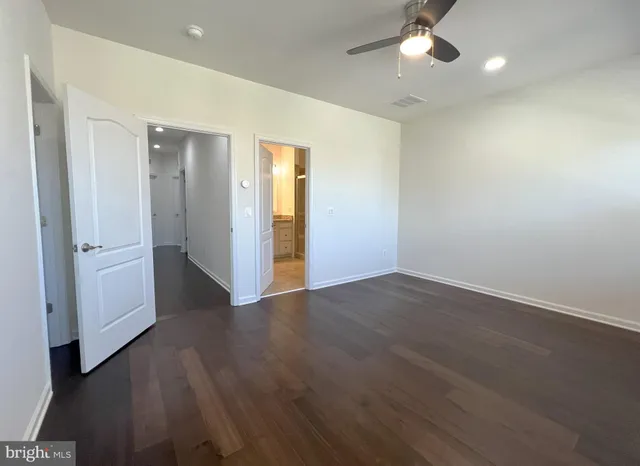 an empty room with wooden floor and ceiling fan