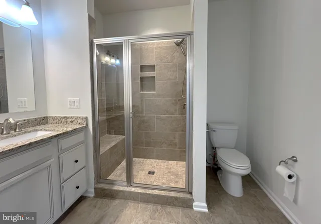 a bathroom with a granite countertop sink a toilet and shower