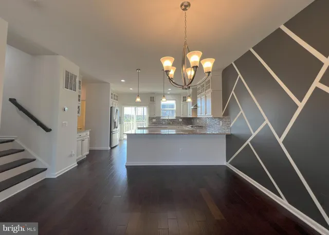 a view of a room with wooden floor staircase and kitchen view