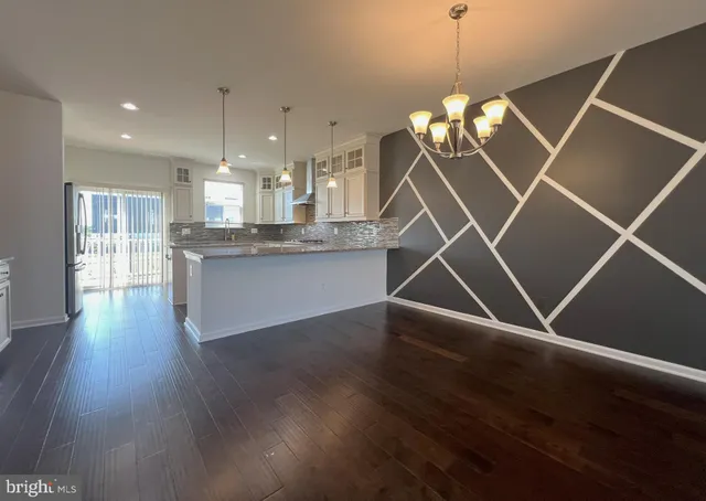 a kitchen with kitchen island wooden floors granite top and stainless steel appliances