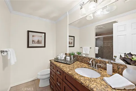 a bathroom with a granite countertop double vanity sink mirror and toilet