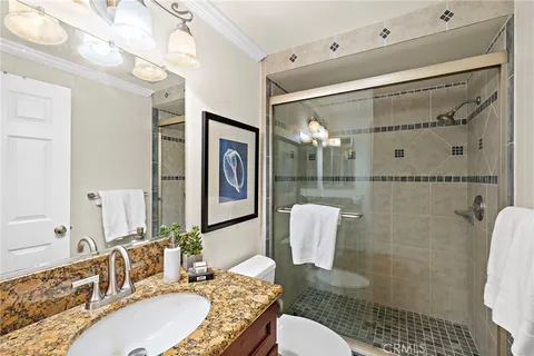 a bathroom with a granite countertop sink mirror and a shower