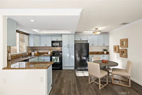 a kitchen with stainless steel appliances granite countertop a refrigerator a stove top oven a sink dishwasher and white cabinets with wooden floor