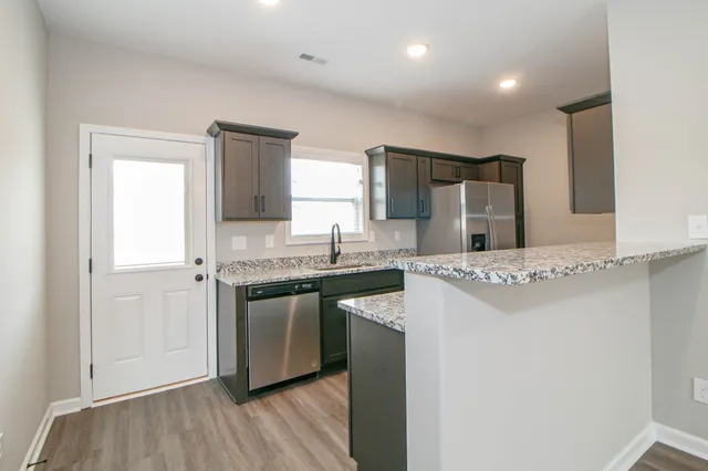 a kitchen with stainless steel appliances granite countertop a refrigerator and a stove top oven