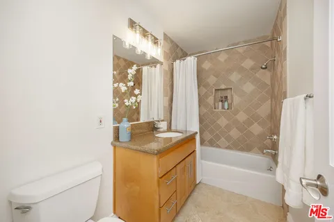 a bathroom with a granite countertop sink a toilet and shower