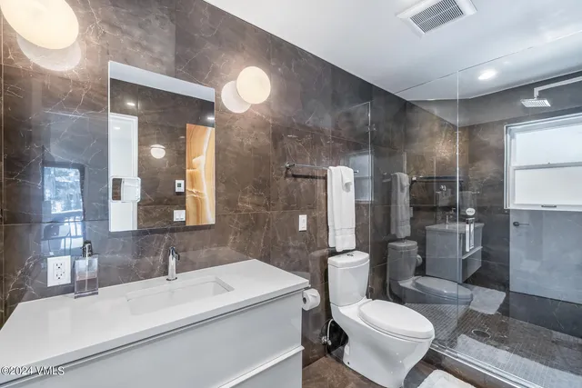 a bathroom with a sink toilet vanity and shower
