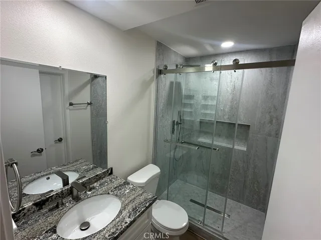 a bathroom with a granite countertop sink toilet and shower