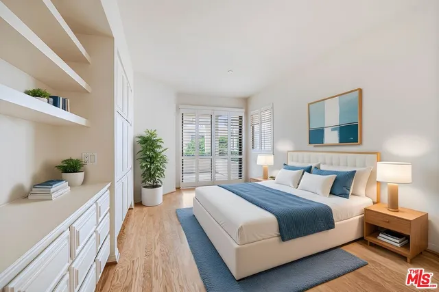 a bedroom with a large bed wooden floor and windows