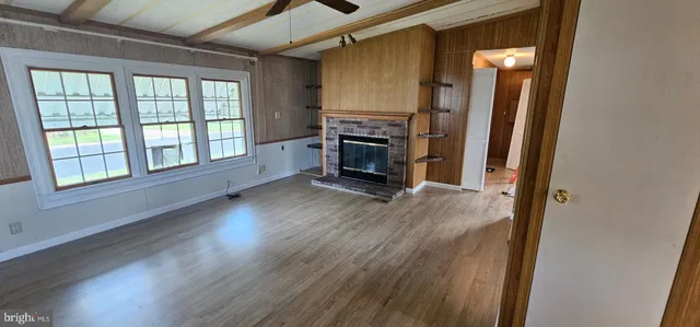 an empty room with wooden floor fireplace and windows