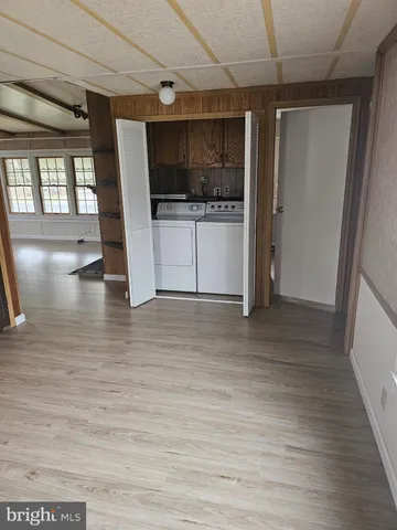 a view of a refrigerator in kitchen and an empty room