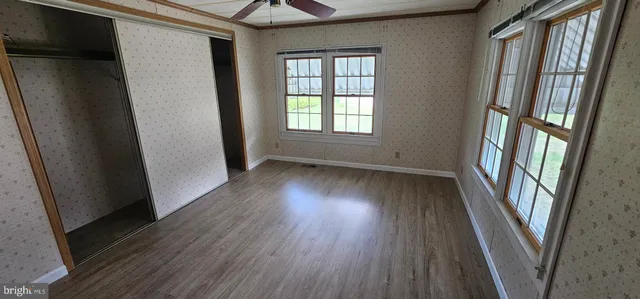 an empty room with wooden floor and windows