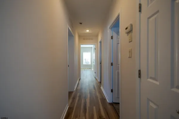 a view of a hallway with wooden floor and a bathroom