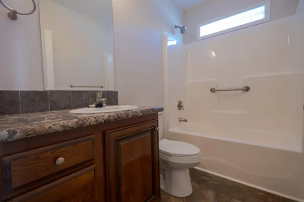 a bathroom with a granite countertop toilet a sink and a bathtub