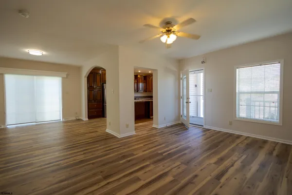 a view of an empty room with a window and wooden floor