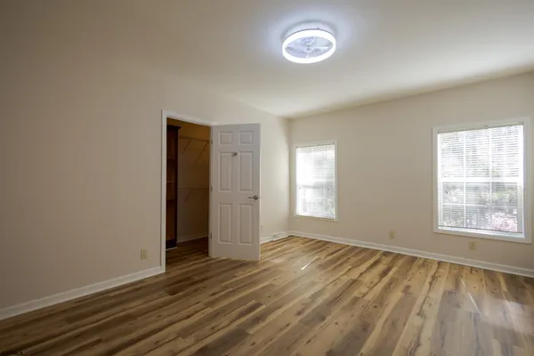 an empty room with wooden floor and windows