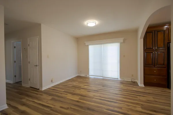 a view of an empty room with wooden floor & cabinets