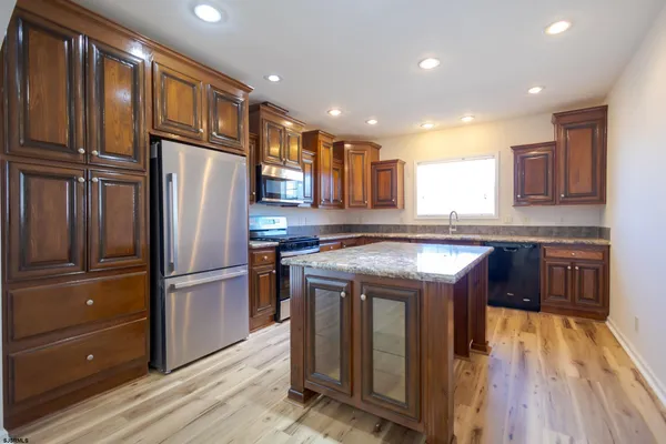 a kitchen with stainless steel appliances granite countertop a refrigerator a stove and a wooden floors