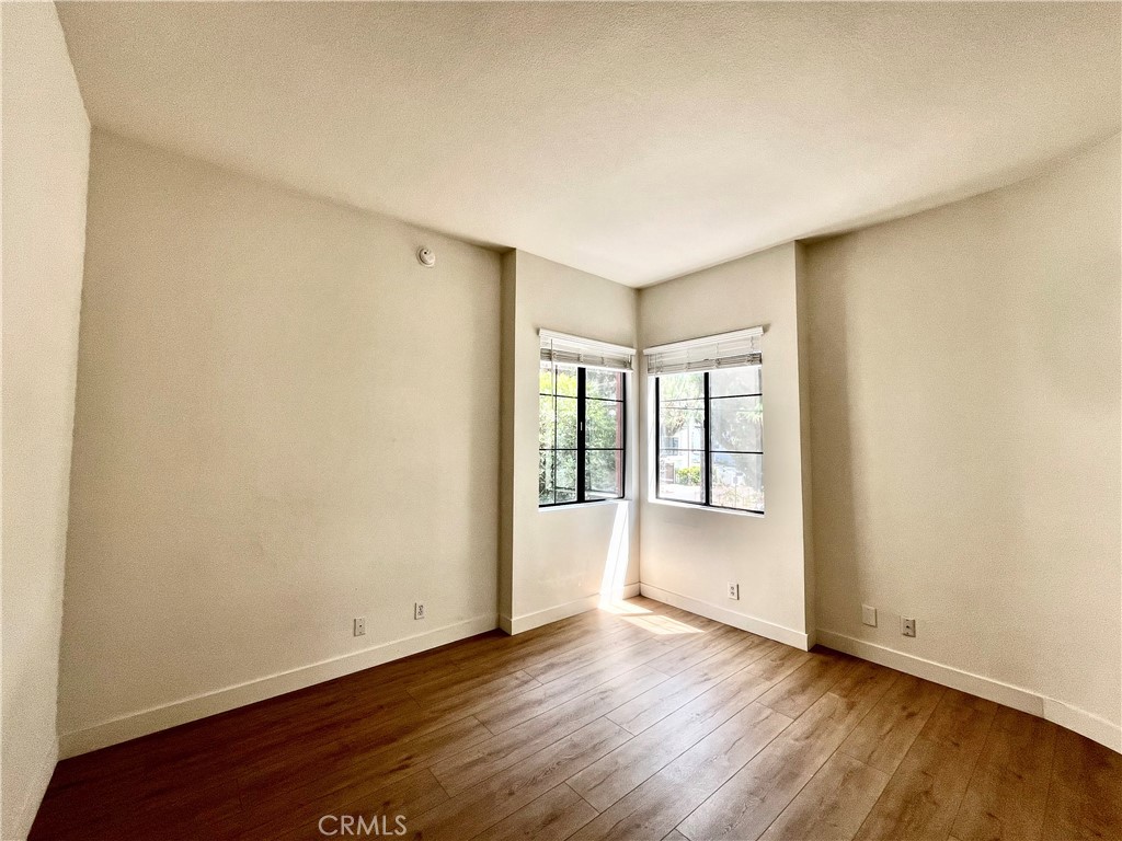 12211 Idaho Avenue, Unit 101 Los Angeles, CA 90025 - Photo 12 of 21 an empty room with wooden floor and windows with curtains