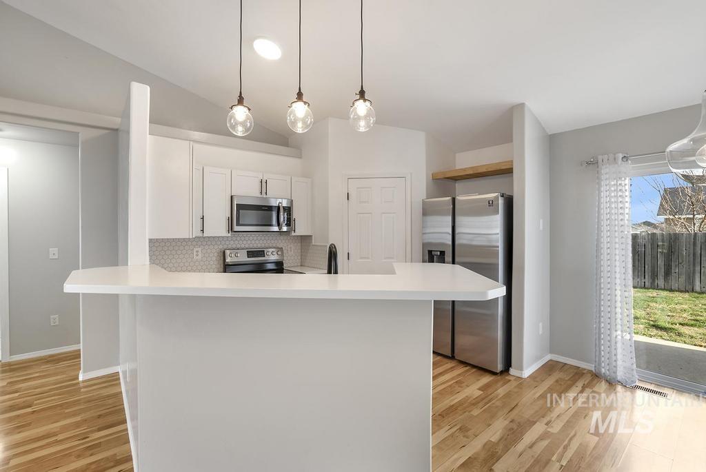 1393 Valencia Street Twin Falls, ID 83301 - Photo 6 of 44 Kitchen with appliances with stainless steel finishes, light countertops, lofted ceiling, decorative light fixtures, and decorative backsplash
