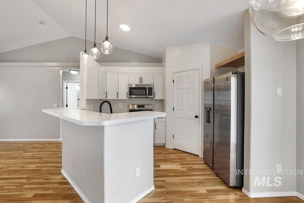 1393 Valencia Street Twin Falls, ID 83301 - Photo 7 of 44 Kitchen featuring light countertops, stainless steel appliances, pendant lighting, vaulted ceiling, and tasteful backsplash