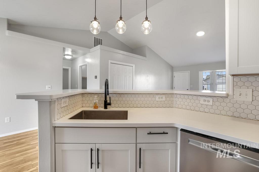 1393 Valencia Street Twin Falls, ID 83301 - Photo 8 of 44 Kitchen featuring dishwasher, white cabinets, backsplash, lofted ceiling, and pendant lighting