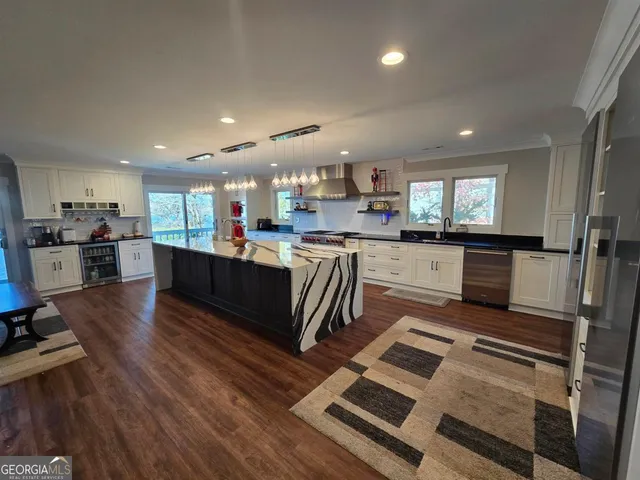 a kitchen with stainless steel appliances granite countertop wooden cabinets a sink dishwasher a stove and a refrigerator with wooden floor