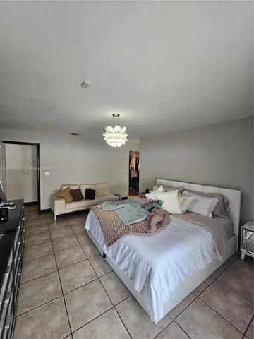 a spacious bedroom with a bed and a chandelier