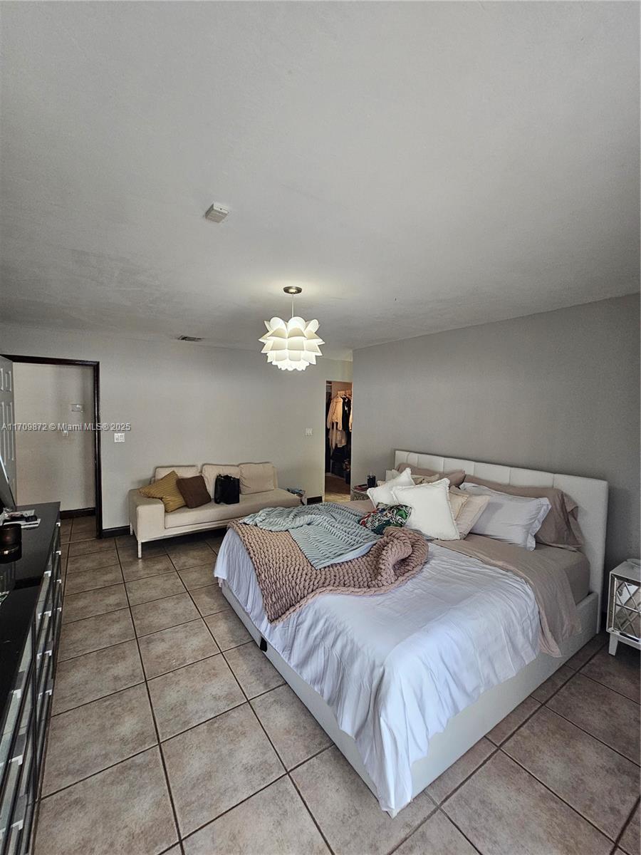14461 Southwest 152nd Court Miami, FL 33196 - Photo 14 of 30 a spacious bedroom with a bed and a chandelier