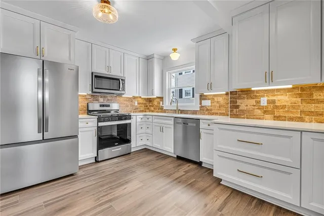 a kitchen with white cabinets stainless steel appliances and wooden floor