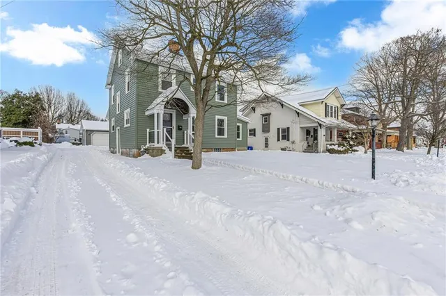 a view of a white house with a yard covered in snow