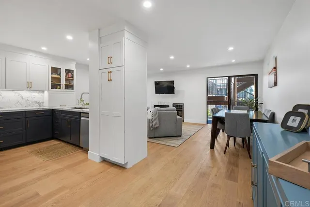 a kitchen with stainless steel appliances kitchen island granite countertop a refrigerator a sink a stove and white cabinets with wooden floor