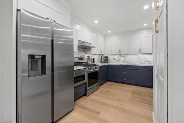 a kitchen with stainless steel appliances kitchen island granite countertop a refrigerator and a sink