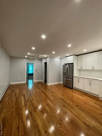 a view of an empty room with kitchen and window
