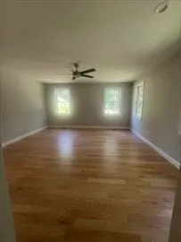 a view of an empty room with window and chandelier fan