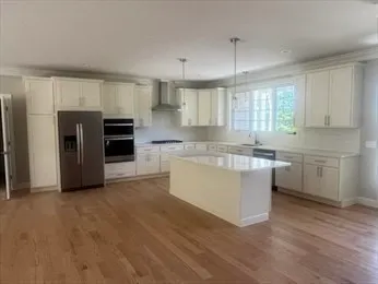 a kitchen with stainless steel appliances a sink a stove a refrigerator and island with wooden floor