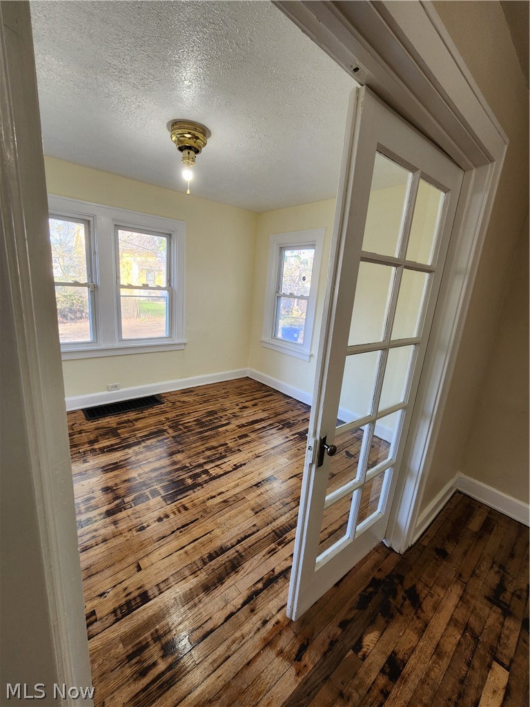13500 Rugby Road Cleveland, OH 44110 - Photo 7 of 18 Spare room with dark hardwood / wood-style floors, french doors, plenty of natural light, and a textured ceiling