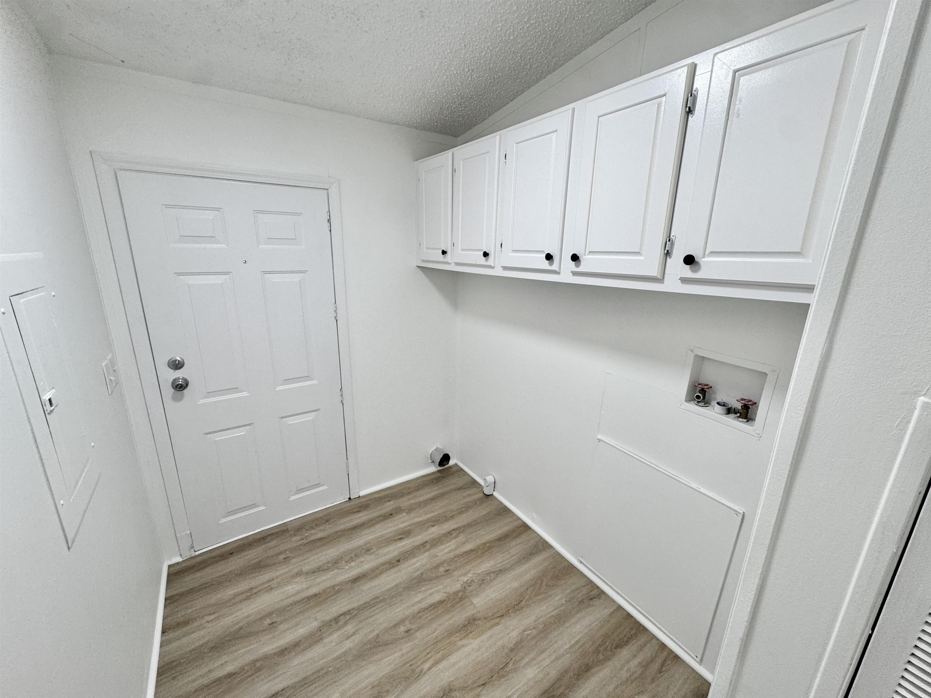 841 Simmons Road Drummonds, TN 38023 - Photo 14 of 35 Clothes washing area featuring cabinet space, hookup for a washing machine, light wood-style floors, and a textured ceiling